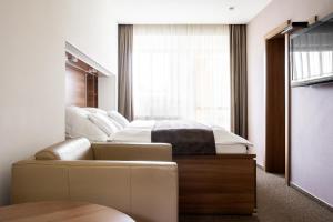 a bedroom with a bed and a couch and a window at Pension Tatrasport Zampa in Starý Smokovec