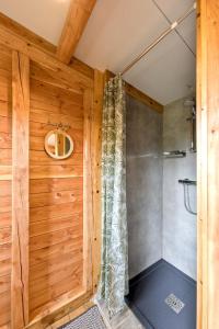 a shower in a room with a wooden wall at La Yourte de la Ferme Froidefontaine in Havelange