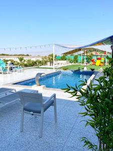 a swimming pool with a table and a chair at Luxury Farm with Swimming Pool and BBQ in Al Rahba