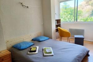 1 dormitorio con cama con almohadas azules y silla amarilla en Entre mer et garrigue, en Saint Pierre La Mer