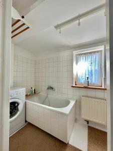 uma casa de banho branca com uma banheira e uma máquina de lavar roupa em Sopot Apartment 54 em Sopot