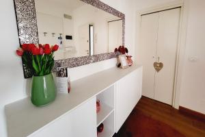La salle de bains est pourvue de tulipes rouges dans un vase vert. dans l'établissement Appartamento Lucia, à Vittorio Veneto