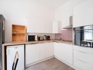 una cocina blanca con armarios y electrodomésticos blancos en Montesquieu * Place Stanislas * Idéal Pros, en Nancy