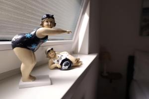 uma figura de uma mulher sentada numa prateleira ao lado de uma boneca em De Blokhut em Egmond aan den Hoef