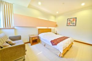 ein Schlafzimmer mit einem Bett und einem Stuhl in der Unterkunft Malia Homestay in Hualien