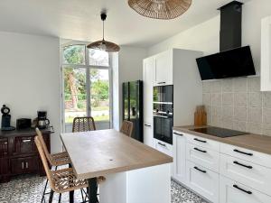 uma cozinha com armários brancos e uma mesa com cadeiras em Gîte des Tourterelles em Épineuil-le-Fleuriel