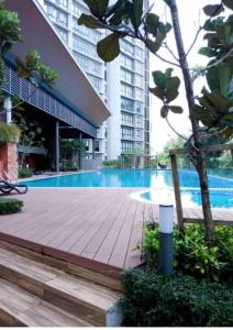 a wooden walkway next to a building with a swimming pool at To Come Again Abode, IOI Resort City, Putrajaya in Seri Kembangan