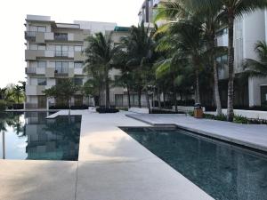 a swimming pool in front of a building with palm trees at By The Sea with Side Seaview n Sunset view #3A2 in Batu Ferringhi