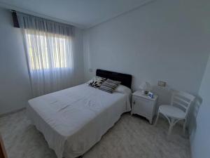 een witte slaapkamer met een bed en een stoel bij Casa Amparo 