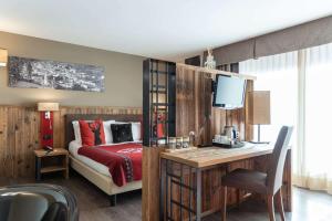 a bedroom with a bed and a desk with a television at Olimpia Hotel in Bormio