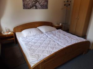 um quarto com uma cama de madeira e lençóis brancos em Ferienwohnung Hahnenkrug em Selk