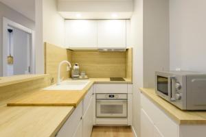 a kitchen with white cabinets and a sink and a microwave at Apartamento Suite Gran Vía in Murcia