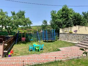un patio con un parque infantil con sillas y un columpio en Casa Ramona en Turda