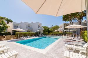 a swimming pool with chairs and umbrellas at Atlas Apartments Ibiza in Santa Eularia des Riu