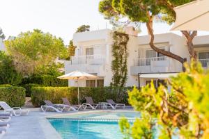 a villa with a swimming pool in front of a building at Atlas Apartments Ibiza in Santa Eularia des Riu
