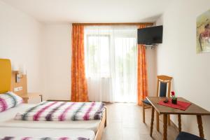 Schlafzimmer mit einem Bett, einem Tisch und einem Fenster in der Unterkunft Bed & Breakfast Eckwirt in Sankt Kanzian am Klopeiner See