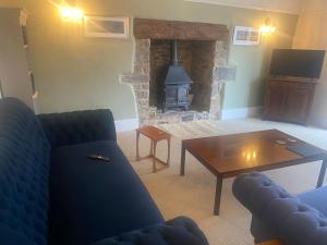a living room with a couch and a table and a fireplace at Upcott Farm in Lapford