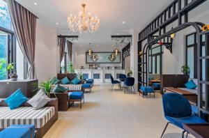 a living room with blue chairs and a chandelier at Rex Quang Binh Hotel in Dong Hoi