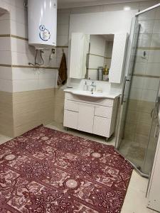 y baño con lavamanos, ducha y alfombra. en Naryn Cozy House en Naryn