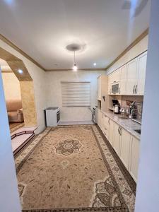 a large kitchen with white cabinets and a tile floor at Naryn Cozy House in Naryn