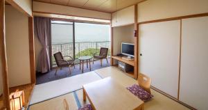 Habitación con balcón con mesa y sillas. en Bizan Kaigetsu, en Tokushima