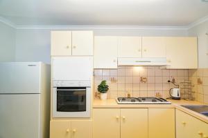 a kitchen with white cabinets and a white refrigerator at COZY 2 BEDROOM HOUSE /MELBOURNE in Werribee