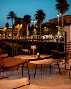 a patio with two tables and chairs and palm trees at Domus Maris Relais Boutique Hotel in Sciacca
