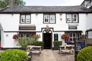 a white house with a black door and flowers at Coach House in High Bentham