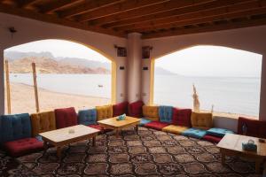 a room with chairs and tables in front of a beach at Abo Hamada Azure Camp in Nuweiba