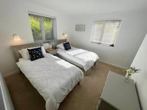 a bedroom with two beds and a table and two windows at Stunning Home with STARGAZING ROOM Near Kielder Water in Greenhaugh