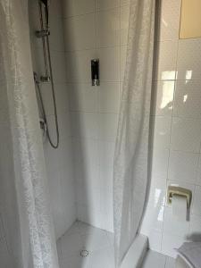 y baño con ducha con cortina blanca. en Case Vacanza Villa Bentivoglio en Piazza Armerina