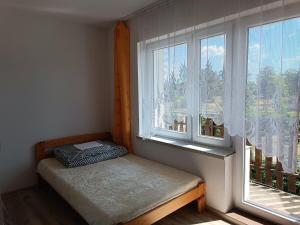 a small bed in a room with two windows at Pokoje Gościnne Heland in Jastrzębia Góra