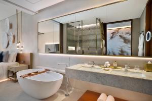 baño con bañera y espejo grande en The St. Regis Downtown Dubai en Dubái