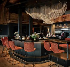 a bar in a restaurant with red chairs at jezz AlmResort Ellmau in Ellmau