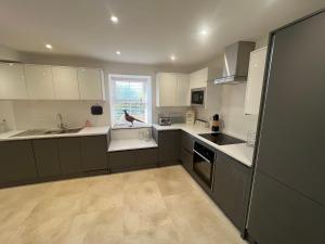 a large kitchen with white cabinets and a window at Stunning Home with STARGAZING ROOM Near Kielder Water in Greenhaugh