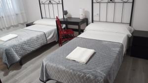 a bedroom with two beds and a desk with a chair at Hostal San Cristobal en Pontedeume in Puentedeume