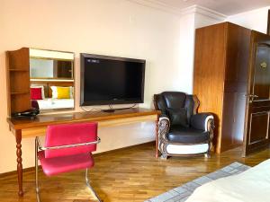 Pokój z telewizorem, 2 krzesłami i łóżkiem w obiekcie Urban Boutique Hotel w Prisztinie