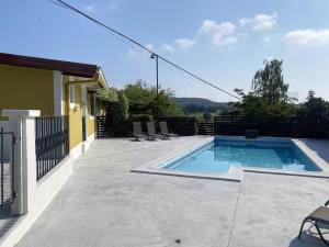 a swimming pool on a patio with chairs next to a house at Precioso apartamento con jardín y piscina in Oruña