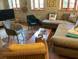 ein Wohnzimmer mit einem Sofa, Stühlen und einem TV in der Unterkunft Der Birkenhof-Ried in Pfaffing