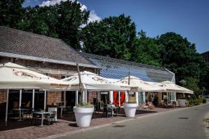 uma fila de mesas e guarda-chuvas em frente a um edifício em KASerne Boutique Hotel em Den Bosch