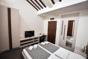 a white bedroom with a bed and a tv at Atrijum Apartments and Rooms - Đerdap Boat Tours in Kladovo