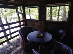 a table and chairs on a porch with two windows at Drinski San in Bajina Bašta