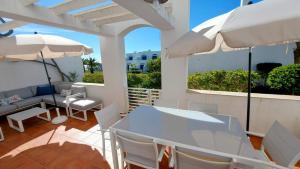 un patio con una mesa blanca, sillas y sombrillas en All Dreams Apartment - Urbanização Windmill, en Albufeira
