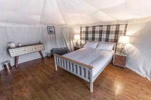 um quarto com uma cama branca e piso em madeira em Glamping in Llanberis em Llanberis