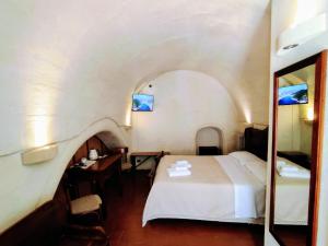 a bedroom with a bed and a desk and a mirror at Cave Rooms Sassi in Matera
