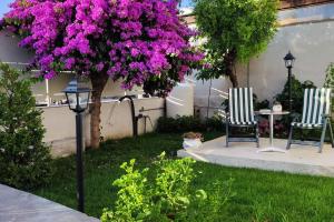 duas cadeiras e uma árvore com flores roxas num quintal em Domus Parva, appartamento con giardino em Pompeia