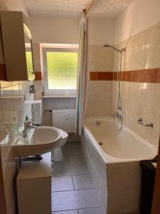 een badkamer met een wastafel, een bad en een toilet bij Ferien am Maar in Daun