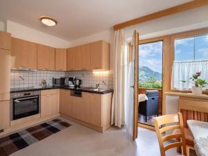 eine Küche mit Holzschränken und einem großen Fenster in der Unterkunft Apart Magdalena in Hainzenberg