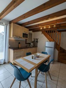 uma cozinha com uma mesa de madeira e cadeiras azuis em Village Océlandes em Saint-Julien-en-Born
