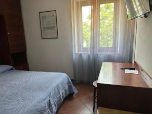 sypialnia z łóżkiem, biurkiem i oknem w obiekcie Hotel Alla città di Trieste w Grado